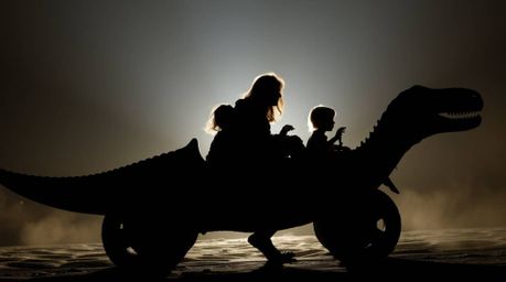 A captivating silhouette of a prehistoric family enjoying a thrilling ride in a dinosaur-shaped car, backlit by a bright ligh