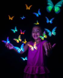 A captivating long exposure photograph showcases a girl releasing bioluminescent butterflies into the night sky.  Their glowi