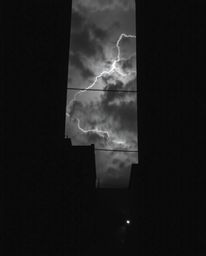 A dramatic black and white photograph capturing the intensity of eyes watching from the shadows of an alley during a stormy n