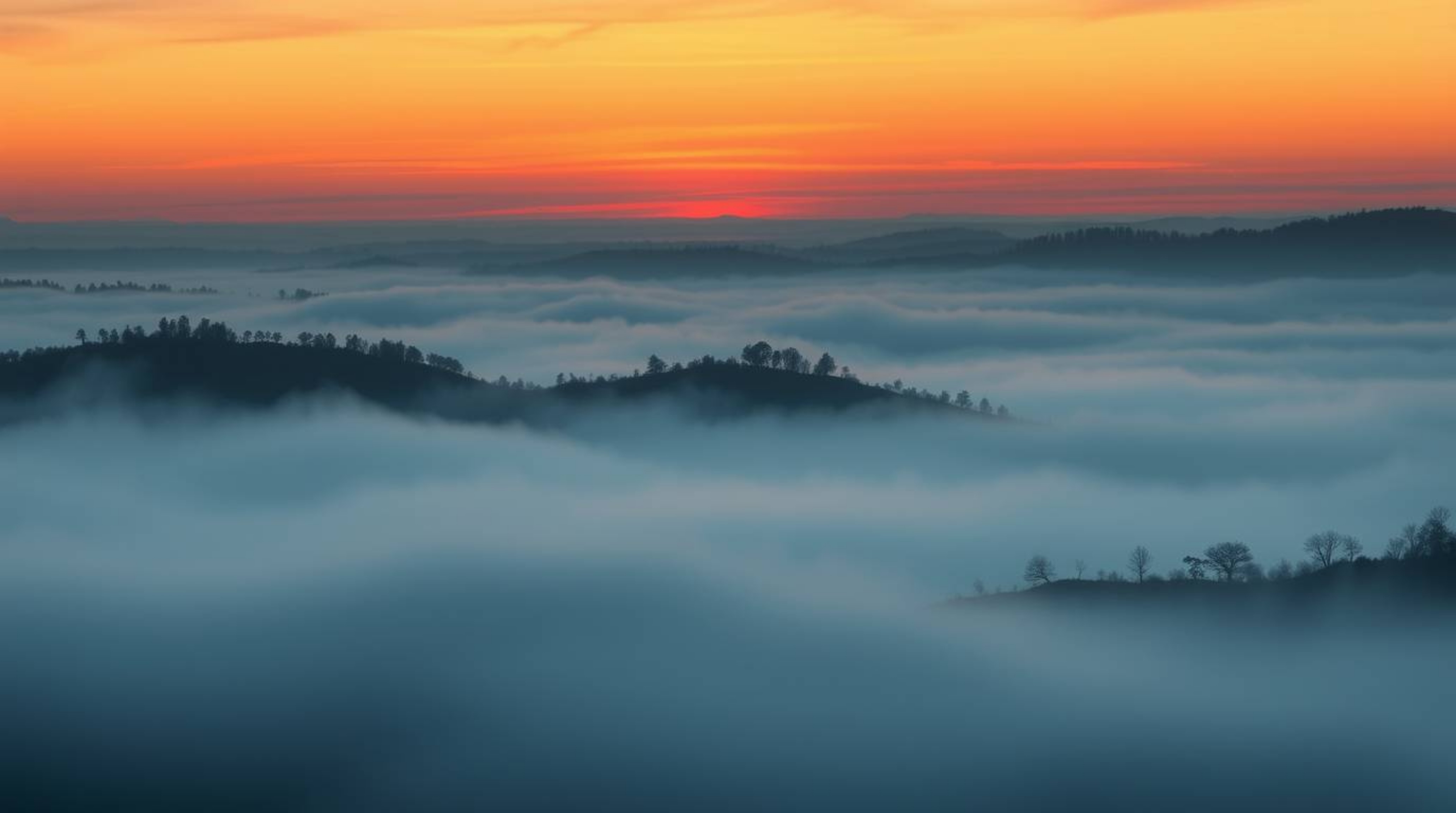 A captivating illustration depicting fog-covered hills bathed in the warm glow of a setting sun. The image features thick fog