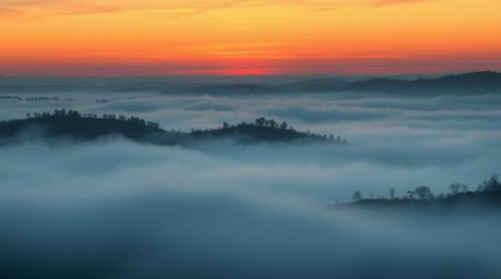 A captivating illustration depicting fog-covered hills bathed in the warm glow of a setting sun. The image features thick fog