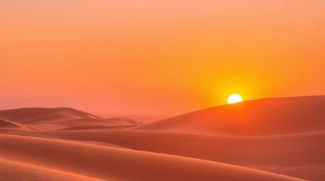 Capture the breathtaking beauty of a sunset over golden desert dunes. This image evokes a vibrant and energetic feeling, with