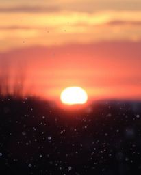 This image exudes an ethereal and spiritual vibe, capturing the magical moment of snowflakes falling during a vibrant sunset.