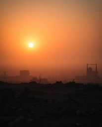 Witness the beauty and resilience in a war-torn landscape as the sun rises, casting an ethereal glow through a soft cinematic
