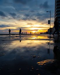 A candid street photography image captures a unique juxtaposition of urban life and natural beauty, showing a sunset sky mirr