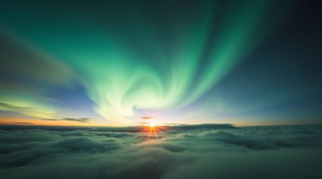 Experience the magic of the Northern Lights dancing across a vibrant sunset sky. This high-angle perspective captures the dre