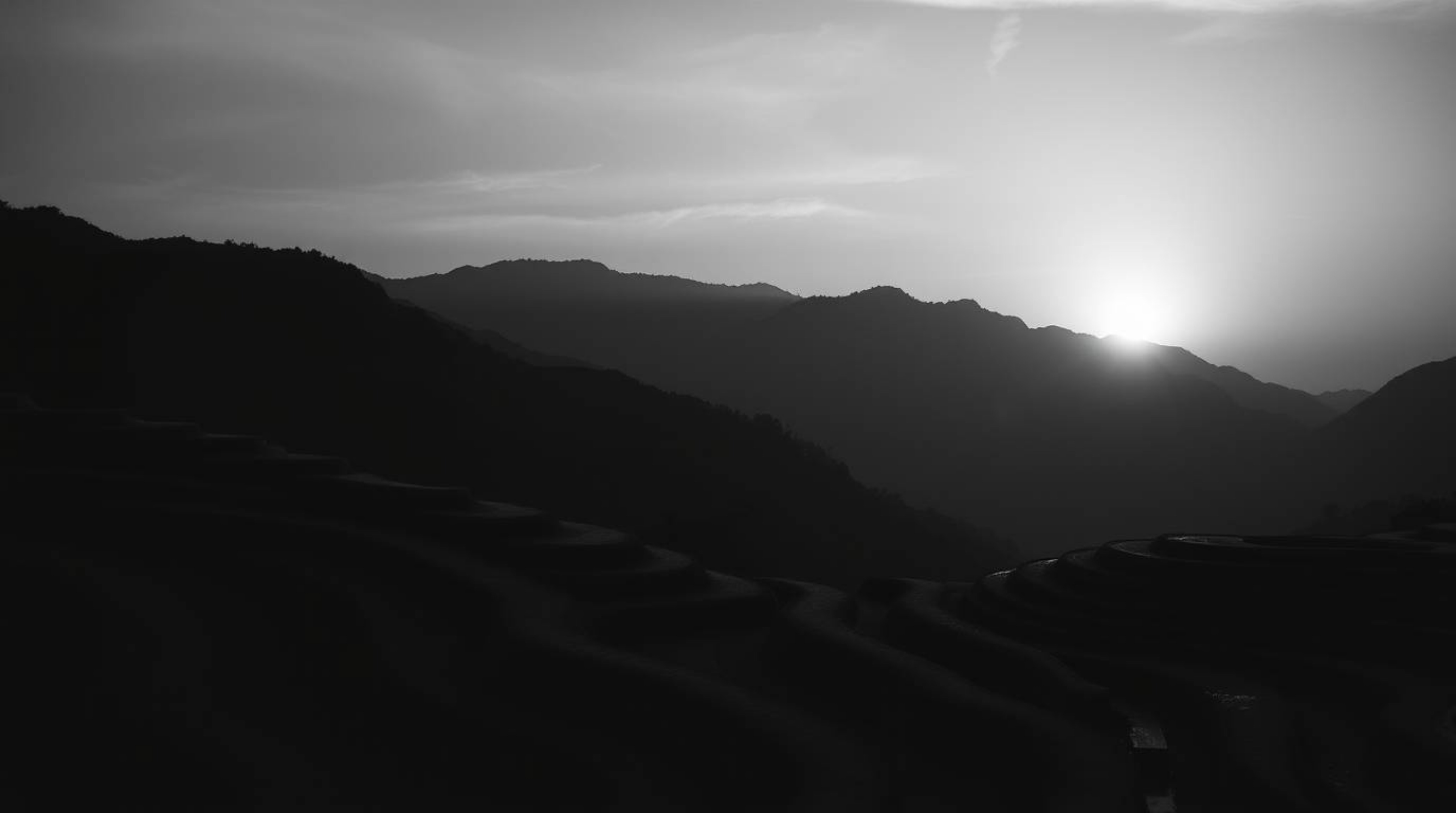 Experience a dramatic and cinematic black and white photograph capturing a timeless and elegant sunset over mountainous rice 