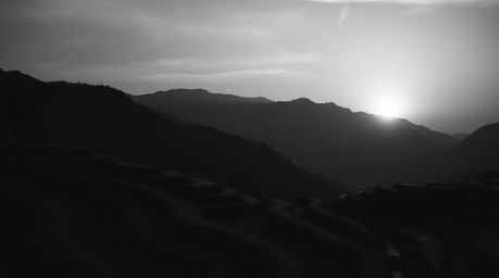 Experience a dramatic and cinematic black and white photograph capturing a timeless and elegant sunset over mountainous rice 
