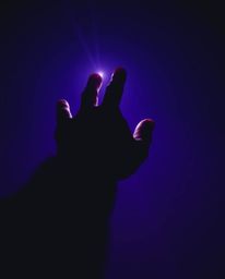 A captivating image depicting a hand reaching towards light from the depths of darkness, rendered in deep ultraviolet hues an