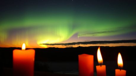 Witness the breathtaking spectacle of the Northern Lights emerging over a vibrant sunset sky.  Warm candlelight illuminates t