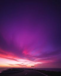 This image showcases a sunset sky over a winding coastal highway, brought to life through a dramatic palette of deep ultravio