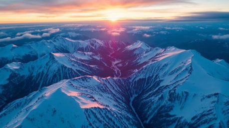Experience a breathtaking bird's eye view of snow-covered mountains bathed in the warm glow of a pastel sunset. This vibrant 