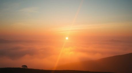 A breathtaking high-resolution stock photo depicting an epic scene of fog-covered hills bathed in the golden light of a drama