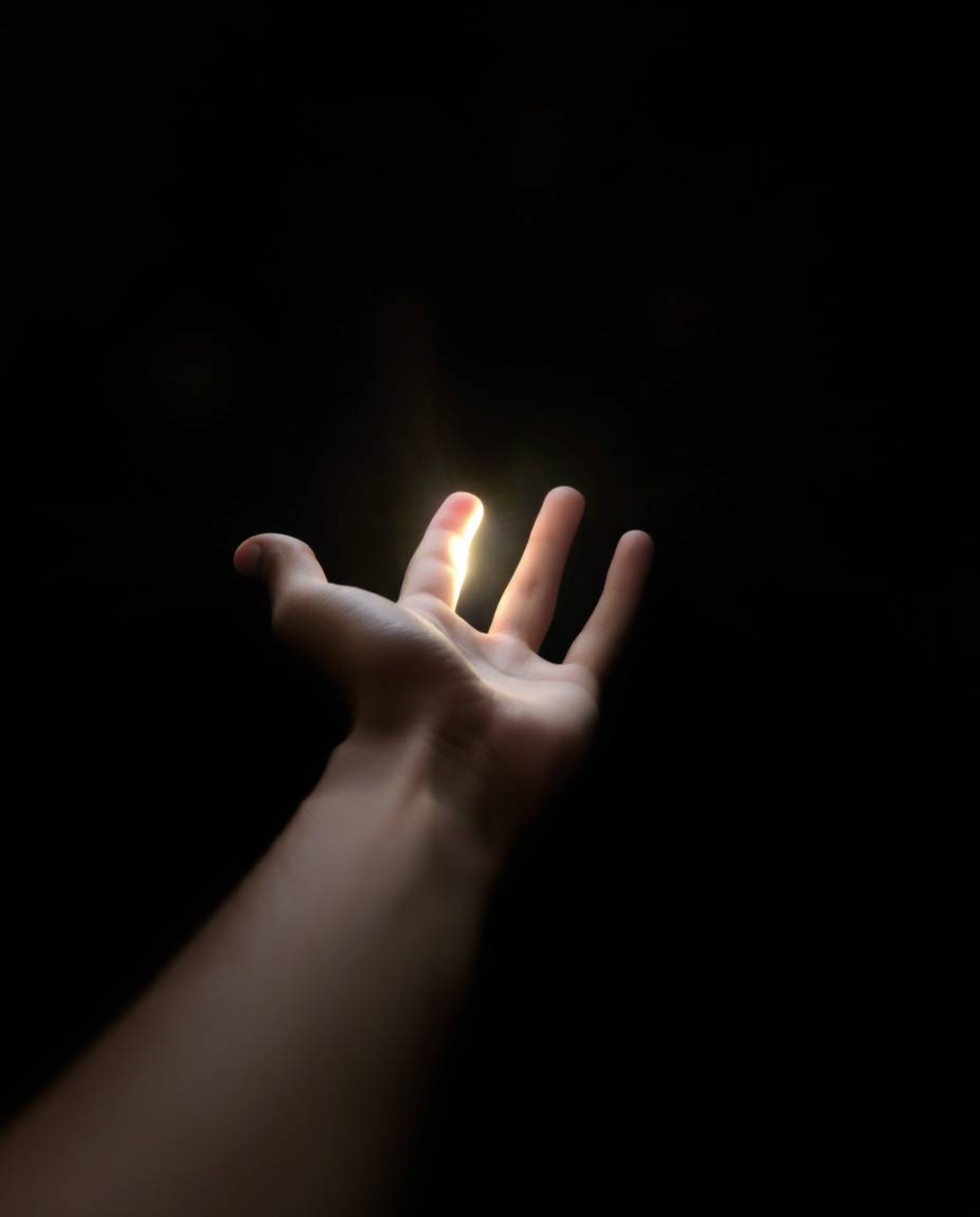This image evokes a sense of hope and reaching for something better, with a hand extending from darkness towards a source of 