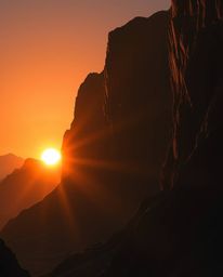 An epic and grand scene captures a sunset illuminating sandstone cliffs, rendered in intense jet black. This powerful artwork