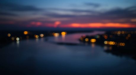 This stunning image captures a river delta bathed in the warm, vibrant colors of twilight. Employing a blurred bokeh effect, 