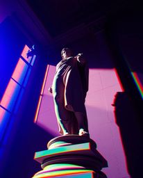 This artwork presents a captivating low-angle view of a classical sculpture, dramatically illuminated by strong, hard light c