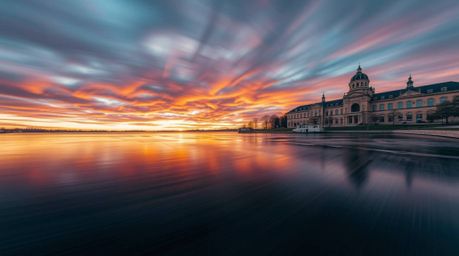 Capture the beauty of architectural design reflected in a serene lake during a vibrant sunset. This photograph showcases dyna