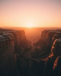 This artwork presents an overhead, bird's-eye view of a sunset illuminating a canyon's sandstone cliffs, all rendered in a be