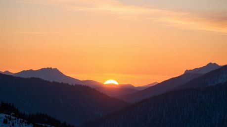 A stunning high-resolution stock photo captures snow-covered mountains bathed in the warm glow of a pastel sunset.  This imag