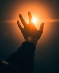 A compelling image featuring a silhouetted hand extending towards a source of light from the darkness, infused with futuristi