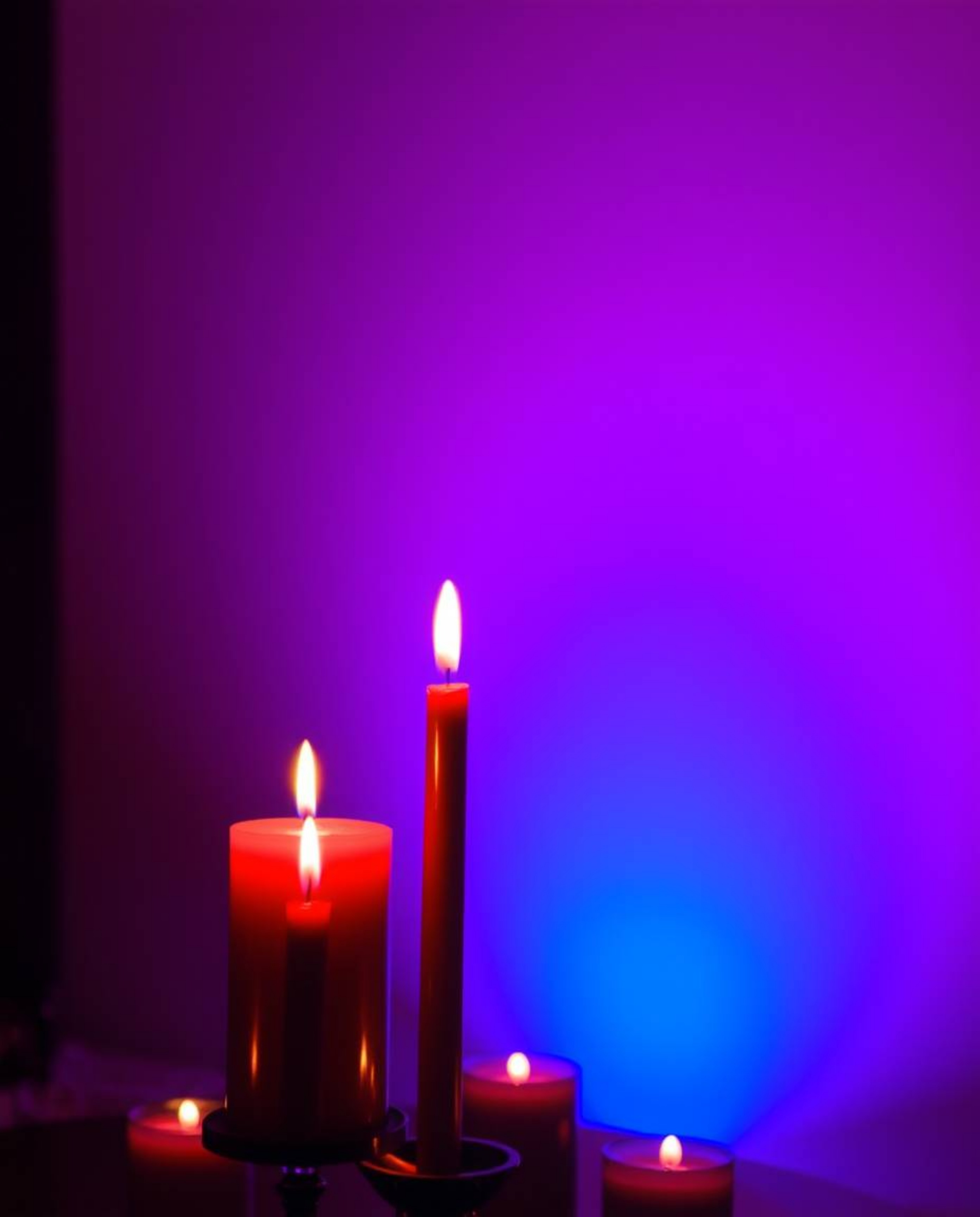 A sophisticated and elegant scene bathed in the warm glow of candlelight, featuring rich burgundy and deep blue tones.  A sof