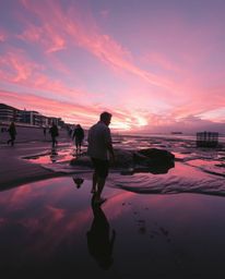 A tight close-up shot, defined by contrasting chiaroscuro lighting, depicts a sunset sky mirrored in the still waters of tida