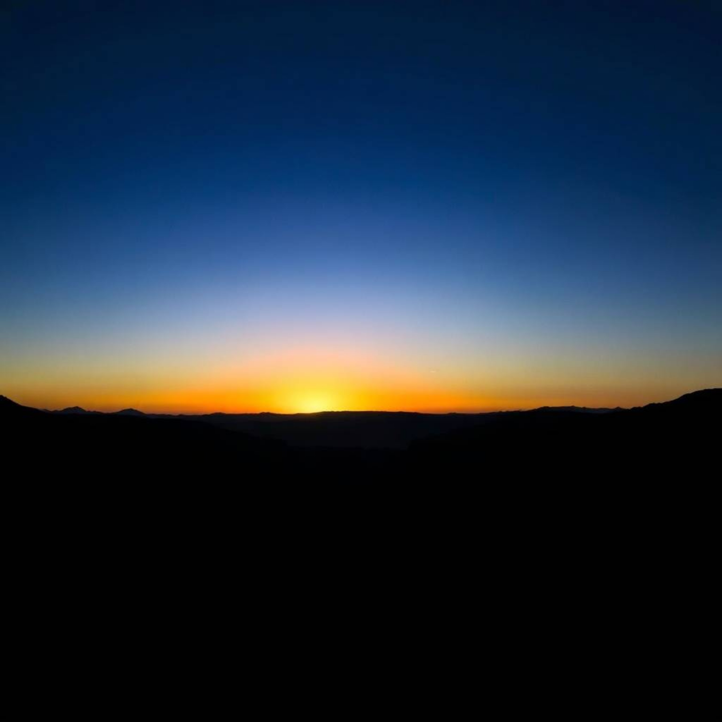 This image captures a serene sunset over a quiet mountain valley, employing dramatic chiaroscuro lighting to highlight the co