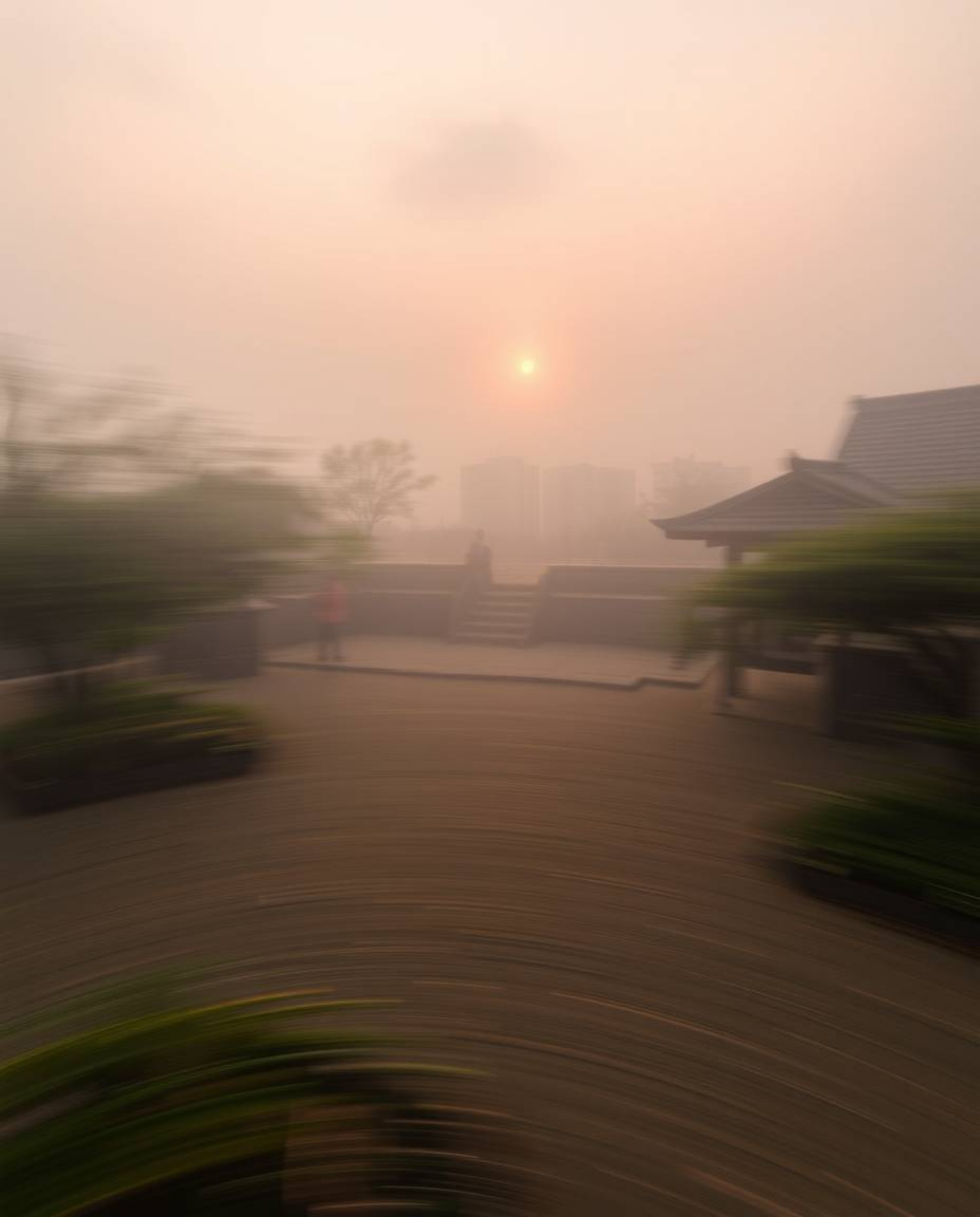 Dynamic motion blur depicting a foggy Zen garden at sunset, low visibility, blurred lines, action poses suggested.