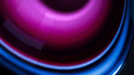 A sophisticated close-up of a glass object showcasing a smooth gradient texture with rich burgundy and deep blue hues. This e