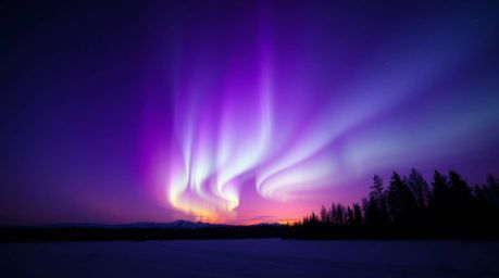 Witness a breathtaking spectacle of the Northern Lights emerging over a vibrant sunset sky. This image showcases deep ultravi