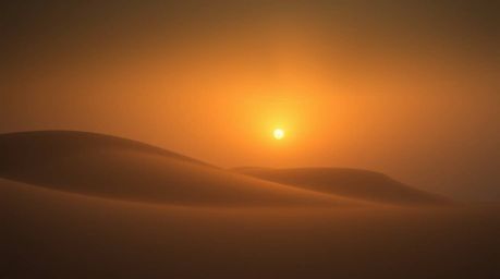 Capture the dreamy, moody atmosphere of a sunset over golden desert dunes.  This image evokes a mystical feel with its low co