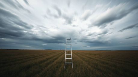A captivating minimalist scene featuring a silver ladder standing tall in an open field beneath a vast, cloudy sky. Photograp