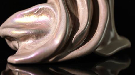 A close-up detail showcasing a sculptural clay art piece with iridescent colors and smooth gradient textures, reflected on a 