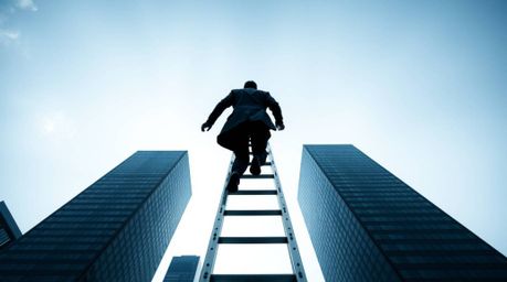 A timeless and elegant black and white photograph depicts a businessperson ascending a transparent ladder that disappears int