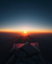 This is an intricate origami-style depiction of a sunset as viewed from a high alpine peak. The artwork is defined by its fol