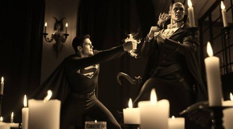 A captivating black and white photograph depicts a classic superhero showdown.  Acaped superhero battles a comical villain un