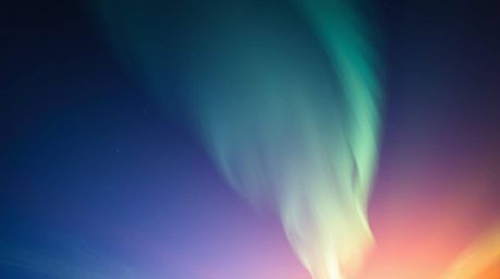 Witness the breathtaking beauty of the Northern Lights dancing across a sunset sky. This image captures a low-angle perspecti
