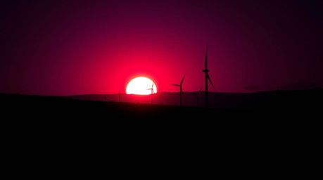 Explore stunning high contrast photography featuring a breathtaking sunset behind wind turbines on a hill. Deep ultraviolet h