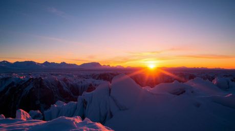 Witness the breathtaking spectacle of a sunset over icy glaciers in the polar region.  Vivid, electric colors paint the sky a