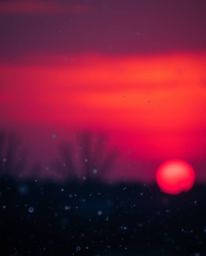 This cinematic style image captures the enchanting scene of snowflakes falling during a vibrant sunset. The composition is ch