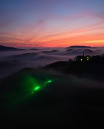 Adorable and charming glowing bioluminescent colors illuminate a sunset over misty Tuscan hills, showcasing natural light eff