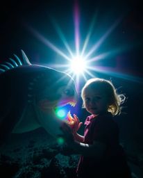 Explore a captivating image featuring a friendship between a sea creature and a child, bathed in bright lens flares and showc