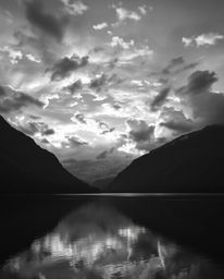 A classic black and white creative light art photograph of a mountain lake reflecting fiery clouds. This image emphasizes art