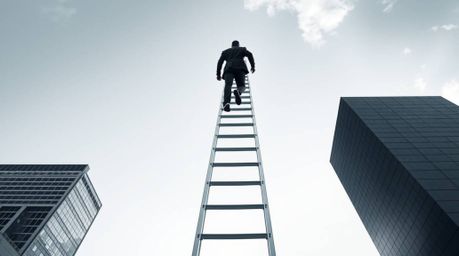 A captivating black and white photograph depicts a businessperson ascending a transparent ladder that disappears into a vibra