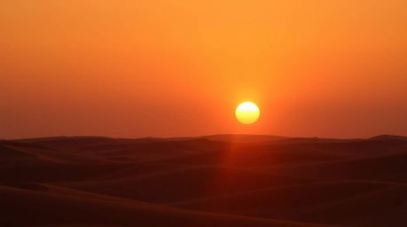 Experience the serene beauty of a sunset over golden desert dunes.  This image captures soft light, diffused shadows, and sub