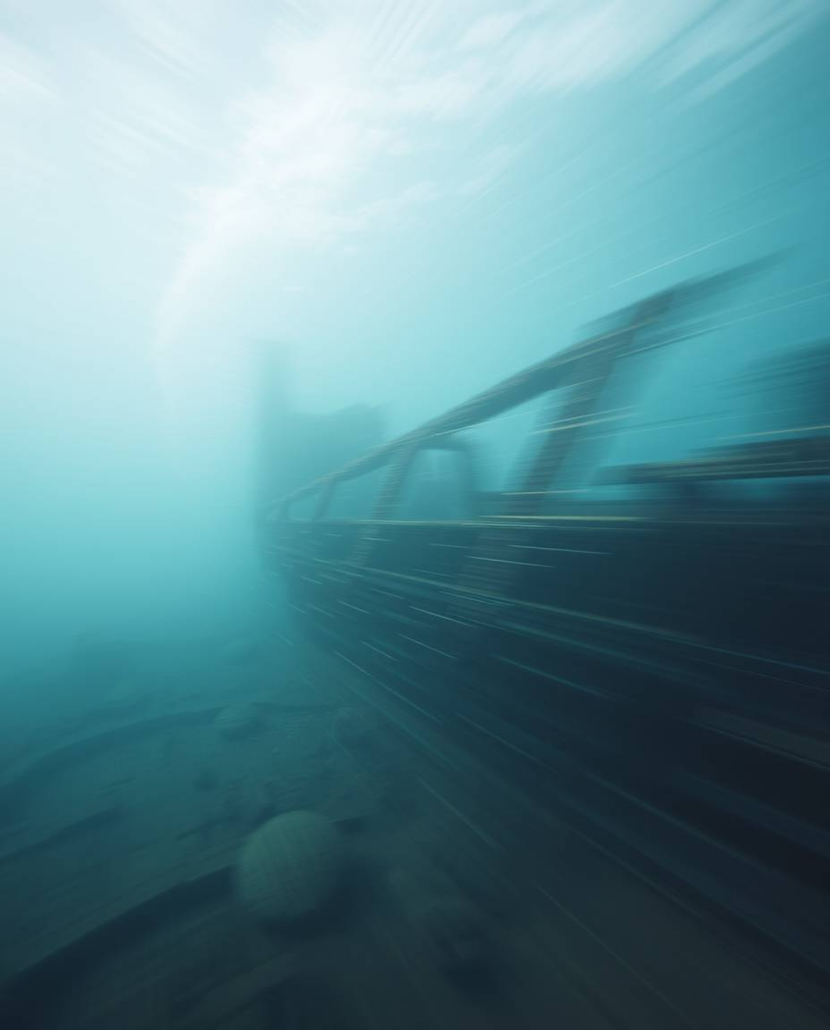 Explore the depths with this dynamic underwater photograph showcasing a motion-blurred shipwreck. Soft light illuminates the 