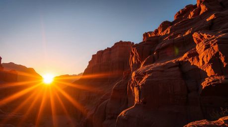 A stunning high-contrast architectural photograph captures a rocky canyon bathed in the warm hues of sunset.  Sharp lines hig