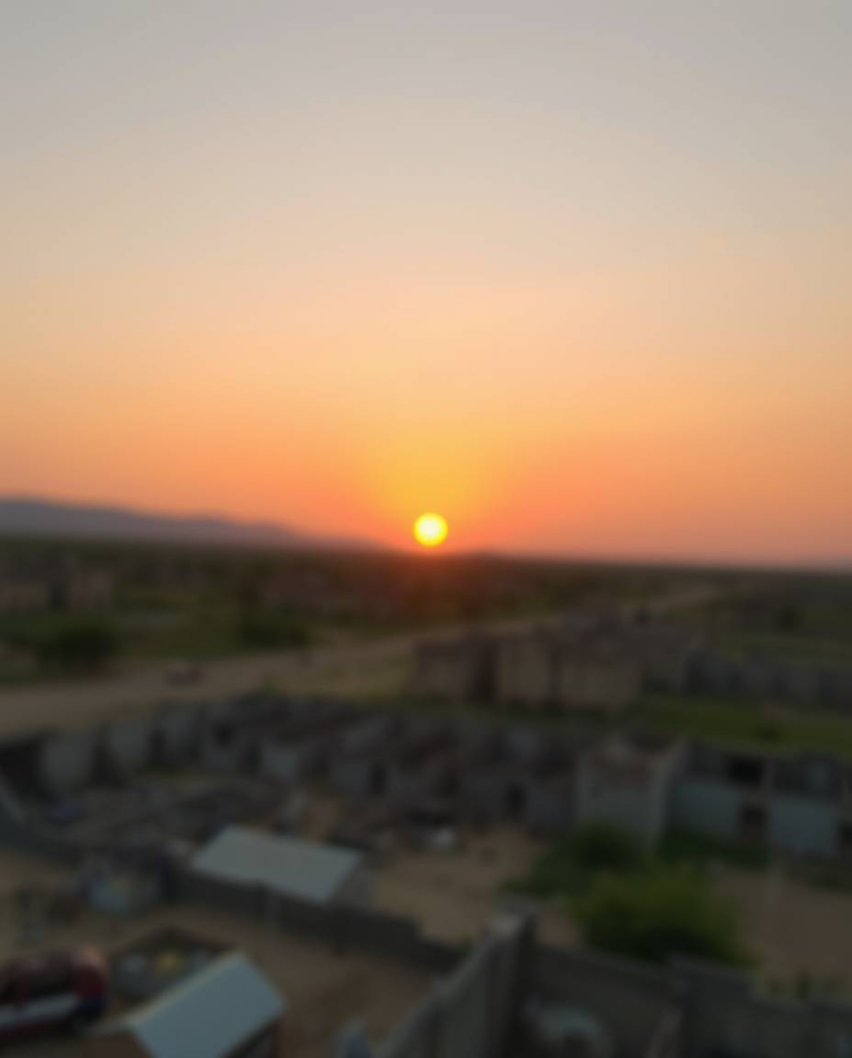 A captivating image depicting a sunrise over a war-torn landscape, featuring a blurred bokeh effect and soft pastel colors. T