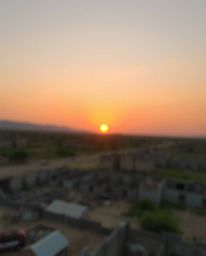 A captivating image depicting a sunrise over a war-torn landscape, featuring a blurred bokeh effect and soft pastel colors. T